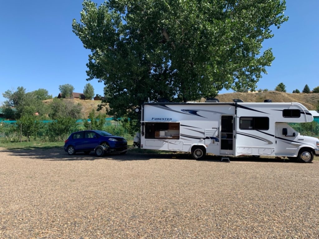 An RV and car sit on a gravel lot in front of a vineyard in South Dakota.