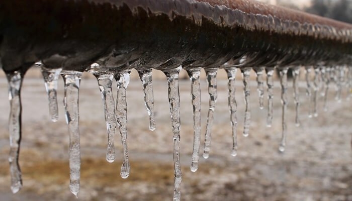 A pipe that has been frozen. There are icicles hanging off of it. 